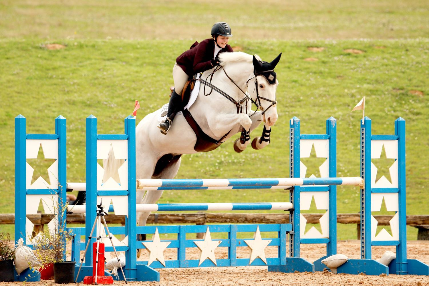 girl riding a white horse jumping over a fence