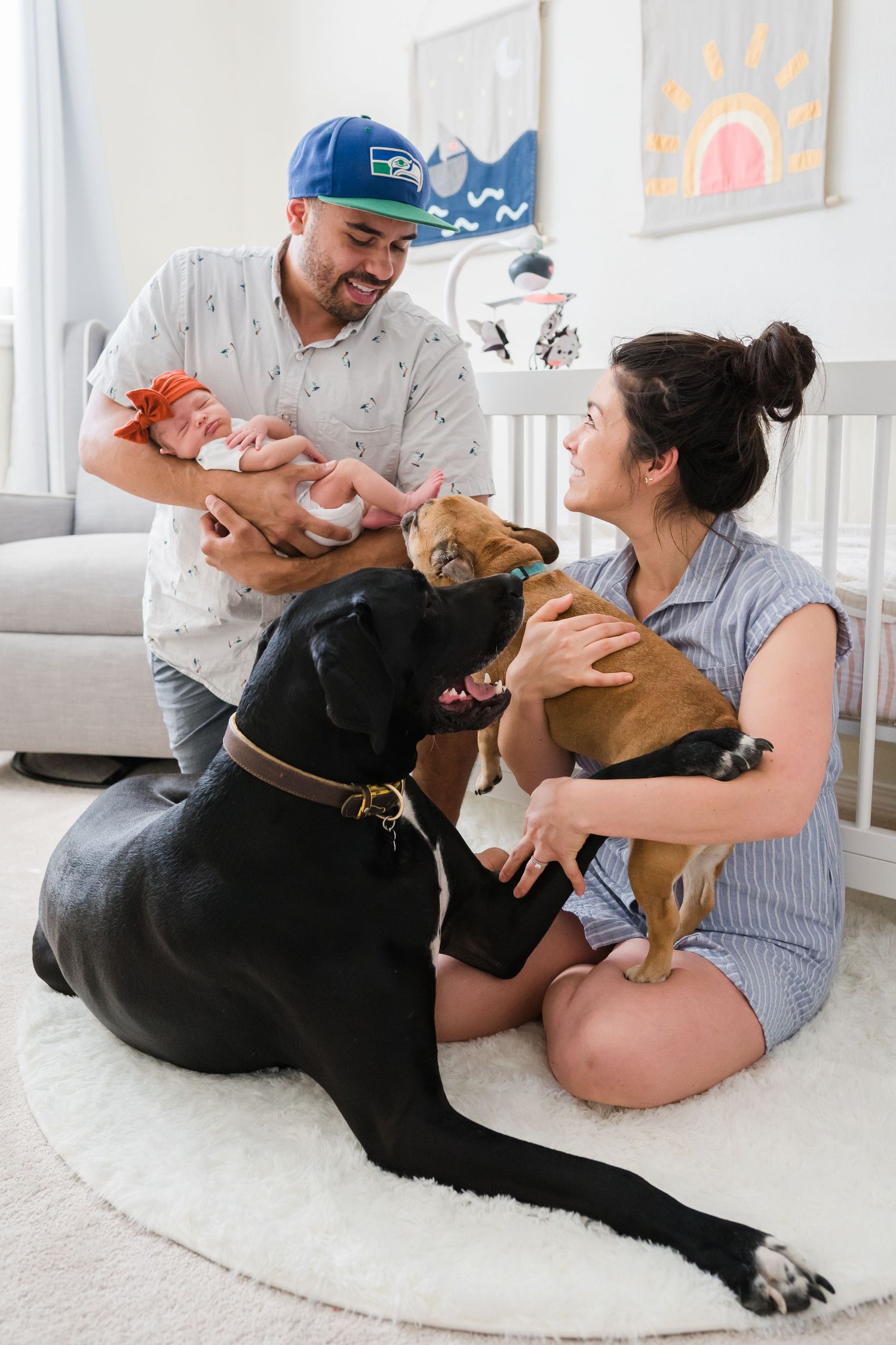 New parents holding baby and petting dogs