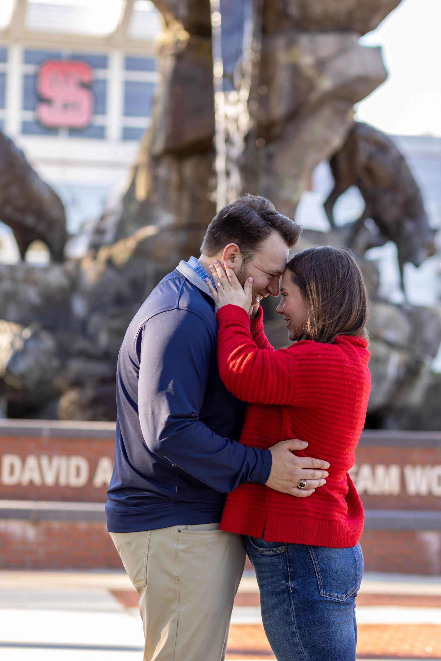 A couple poses in front of the wolf statue at their NC State Engagement Proposal session.