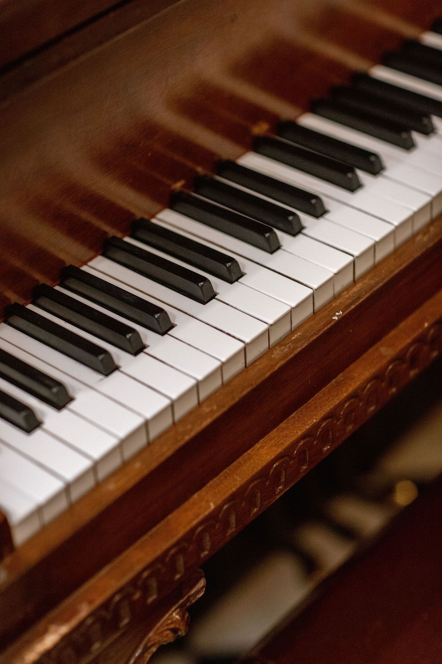 Close-up view of vintage piano keys showing black and white keys on an ornate wooden piano.