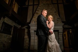 A romantic evening portrait of a wedding couple against a dramatic stone architectural backdrop.