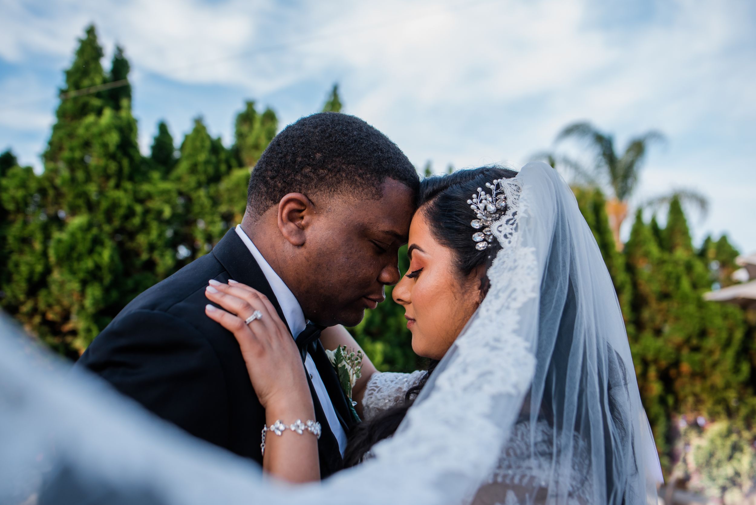 Intimate moment captured between newlyweds during outdoor wedding portrait session.