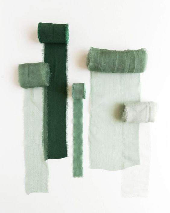 A collection of torn paper samples in various shades of sage green and forest green arranged in a horizontal line.