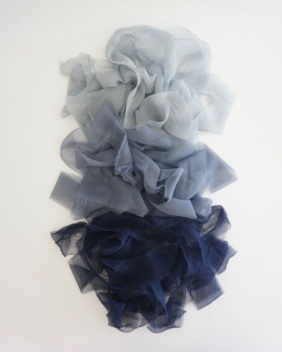 Ruffled fabric transitions from light grey to navy blue in an artistic gradient display.