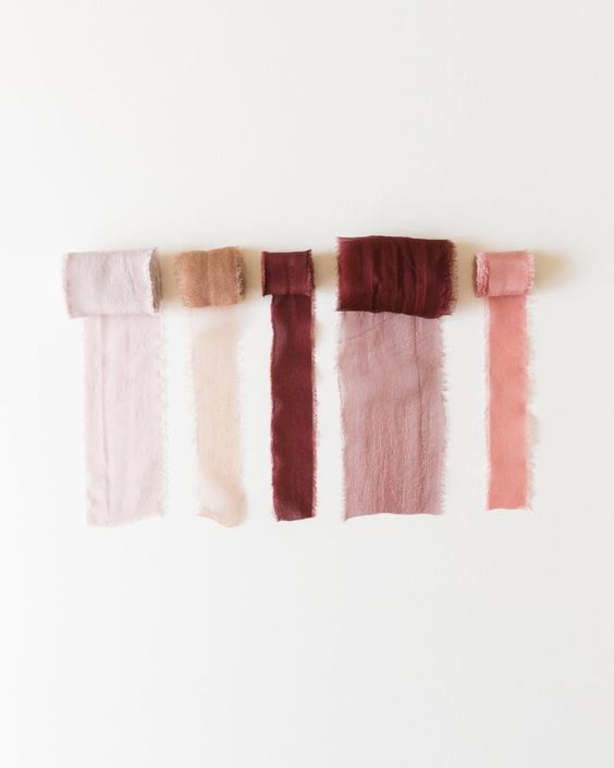 Fabric color samples arranged in a row showing variations of pink and burgundy tones.
