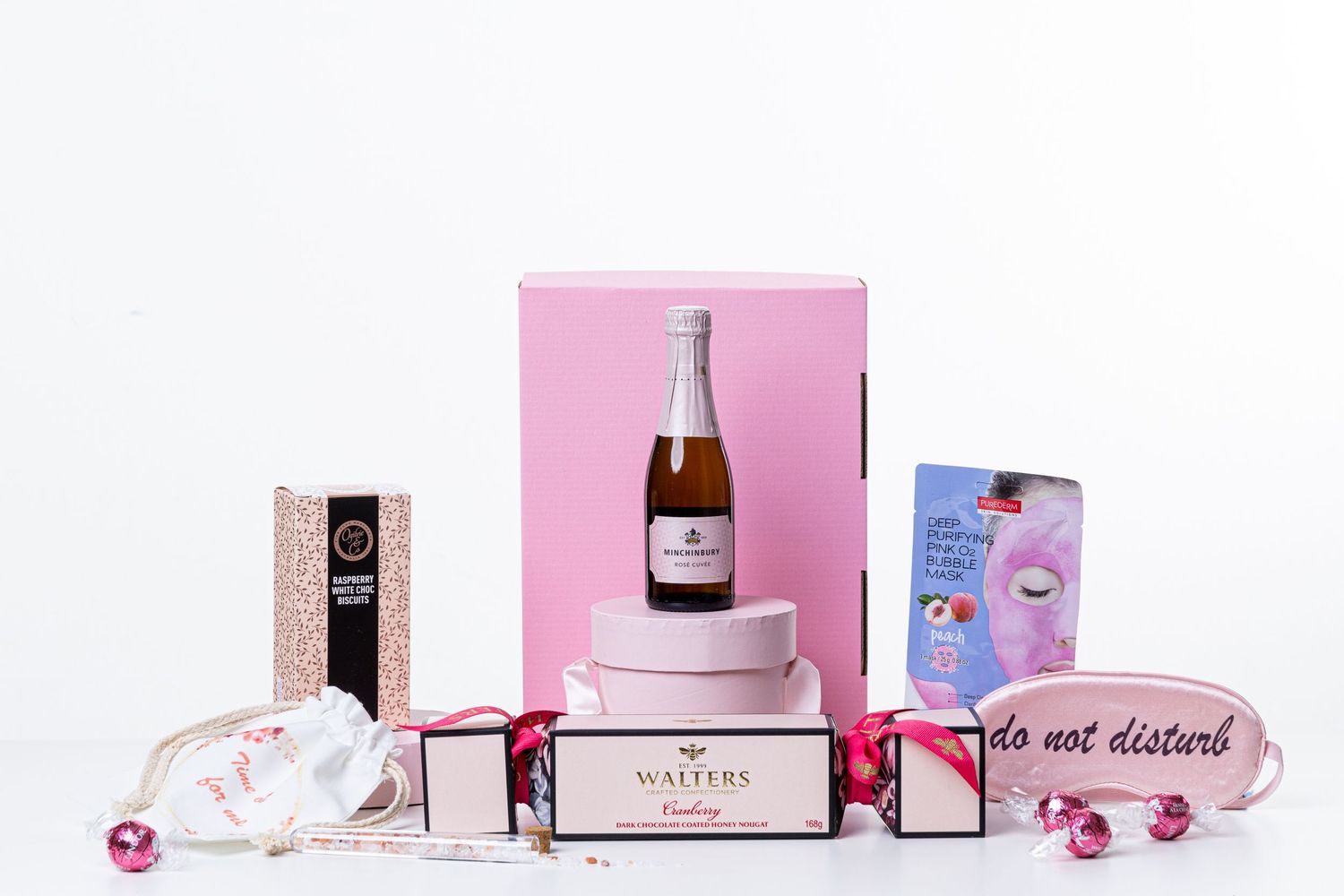 Pink and white gift set with champagne bottle, boxes and decorative elements on white background.