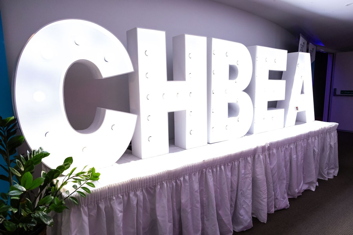 Large white CHBEA letters displayed on stage with draped table skirt.