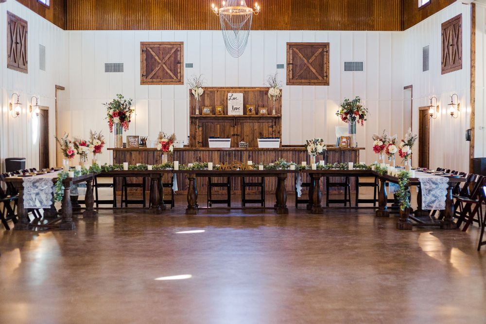 Spacious rustic-elegant wedding venue with wooden beams and white walls.