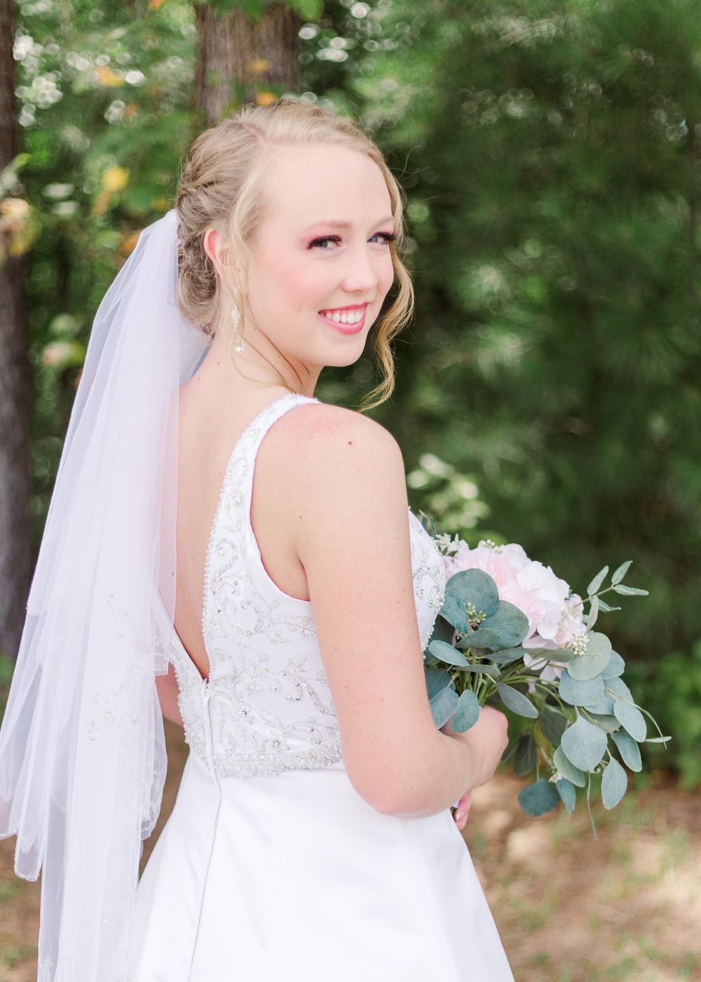 Outdoor bridal portraits featuring flowing veil and eucalyptus bouquet against forest backdrop, by best San Antonio Photographer.