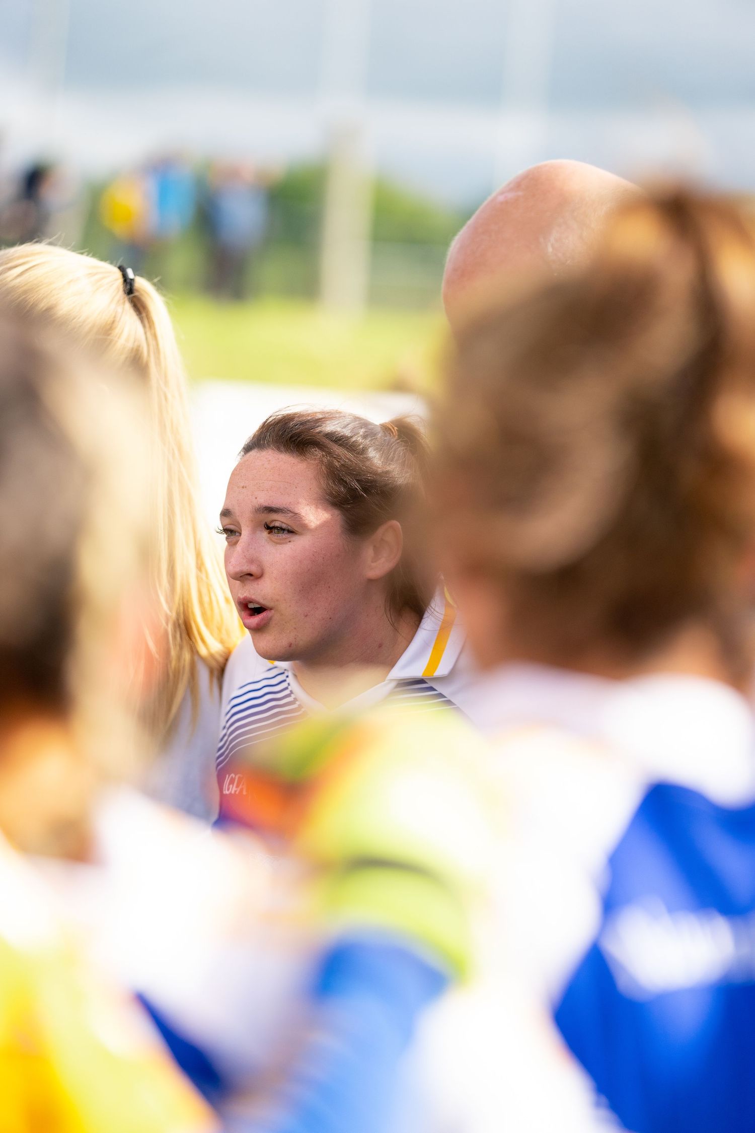 Athletes gathered in a huddle during a sporting event on a sunny day.