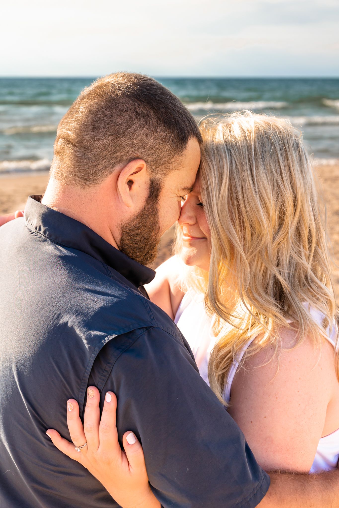 Romantic beach portrait of a couple sharing an intimate moment at sunset.