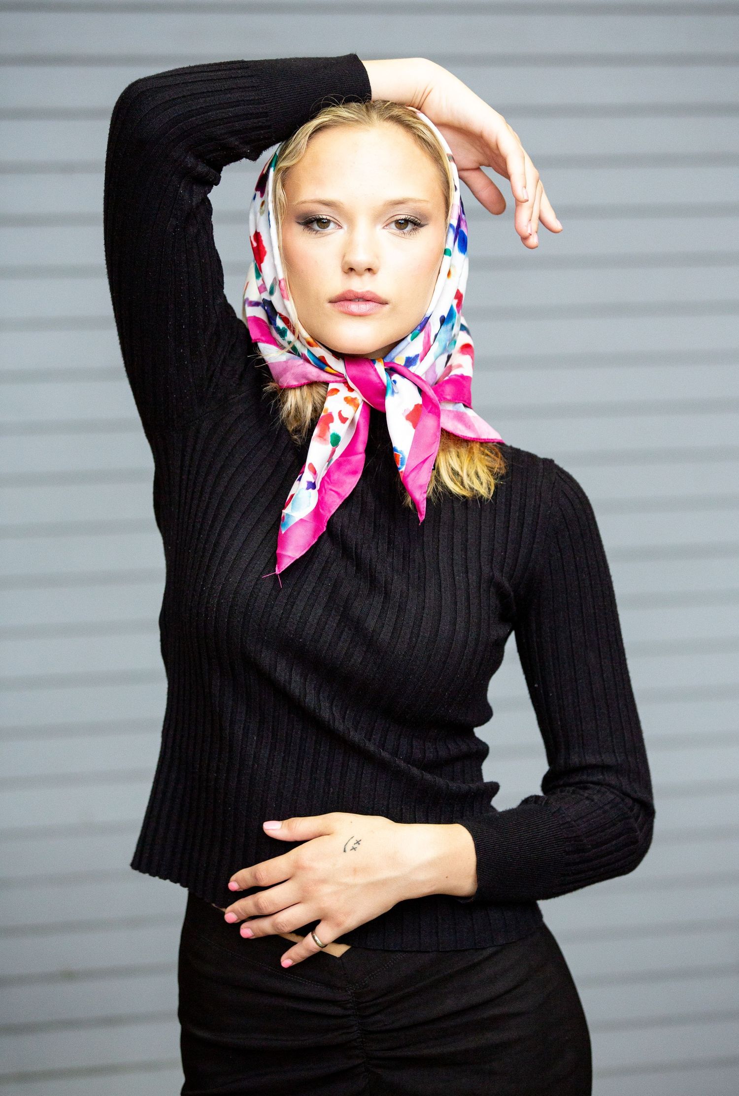 a woman in a black sweater with a pink and blue scarf