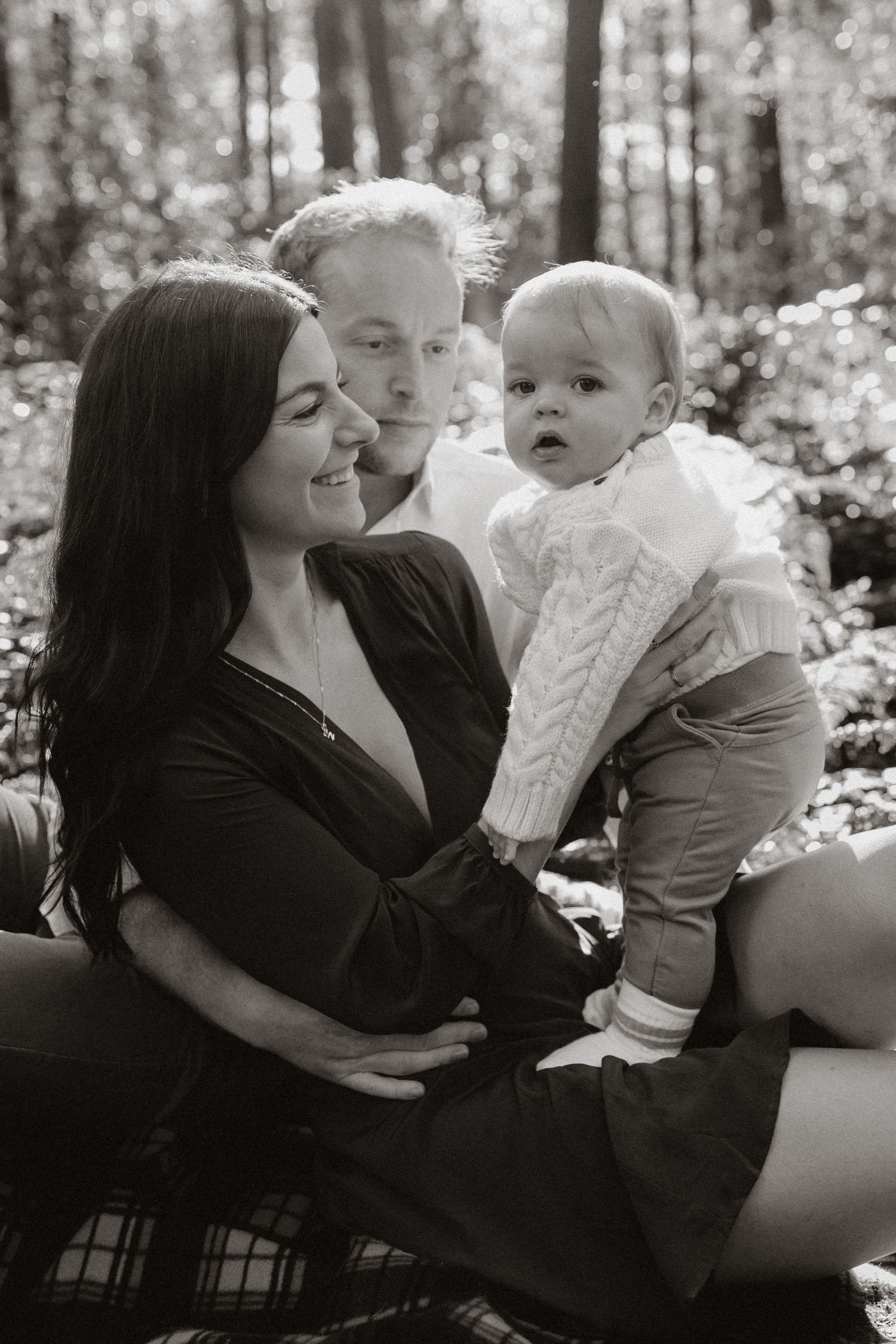 A family of 3 sitting together in the forest in Hampshire for a family photoshoot.