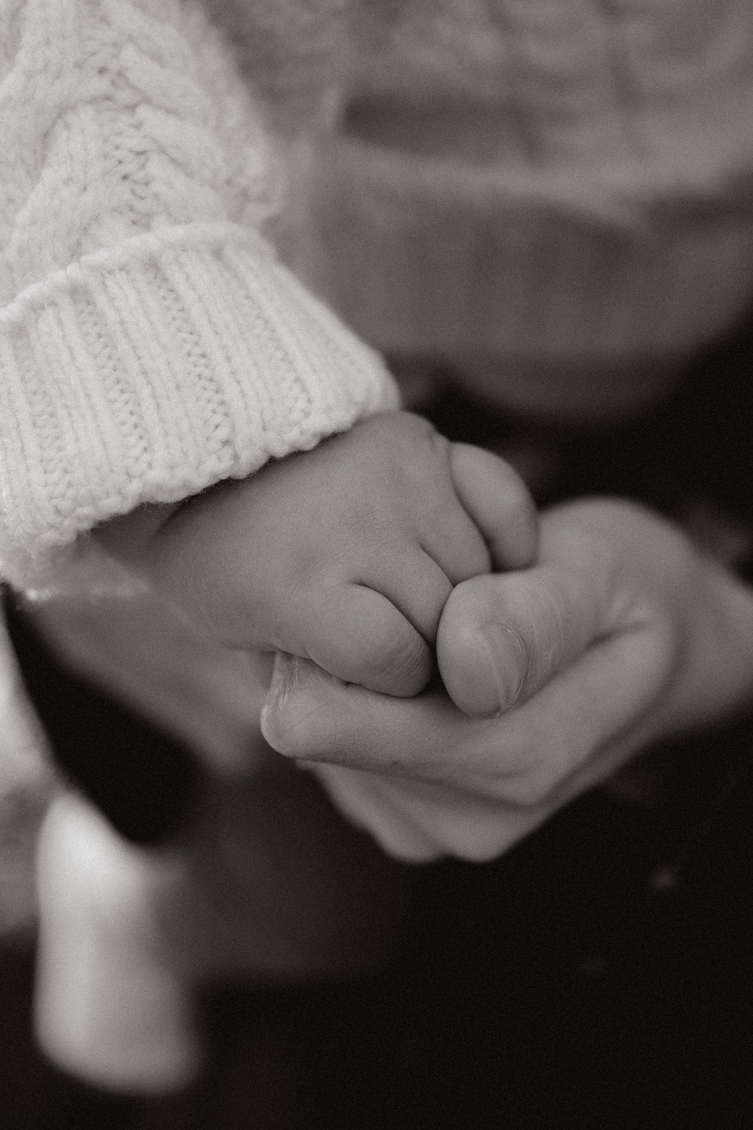 A black and white close up of a baby's hand in his mother hands taken by family photographer Liz Corrigan.
