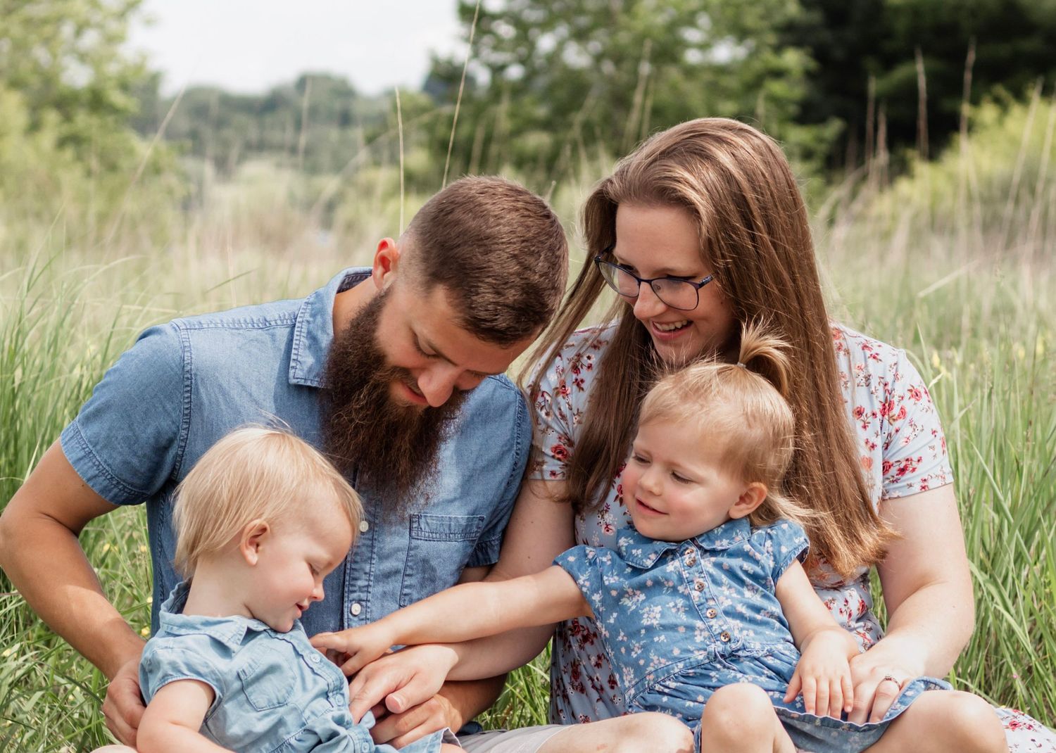 Happy family sitting together in a grassy meadow on a sunny day.
