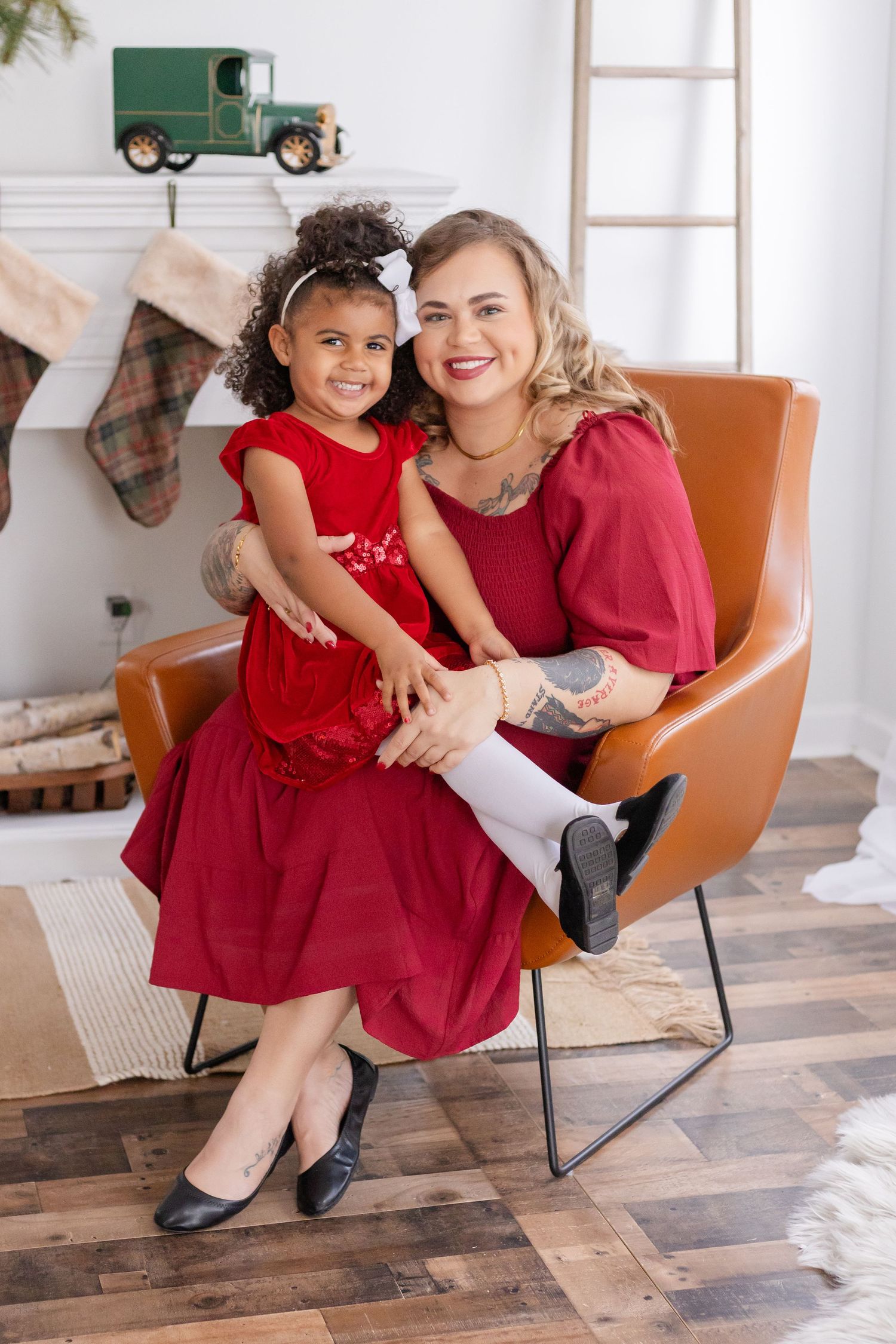 A festive holiday portrait in matching red outfits sitting in an orange accent chair.