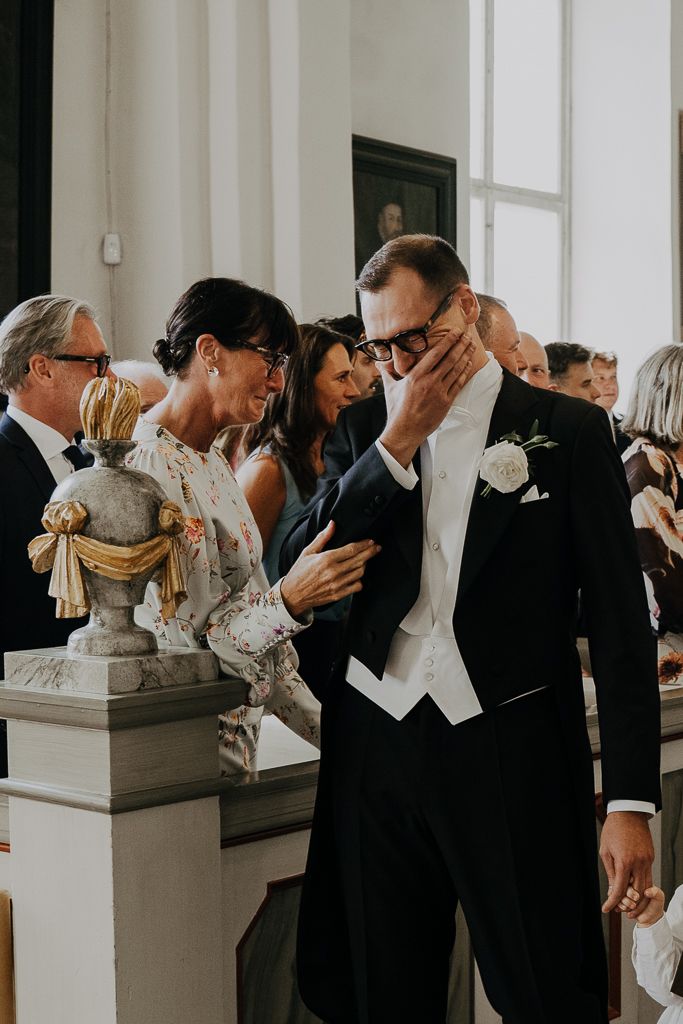 Brudgummen har ett känslosamt ögonblick med sin mamma. Bröllopsfotografering i Kolbäck utanför Västerås.