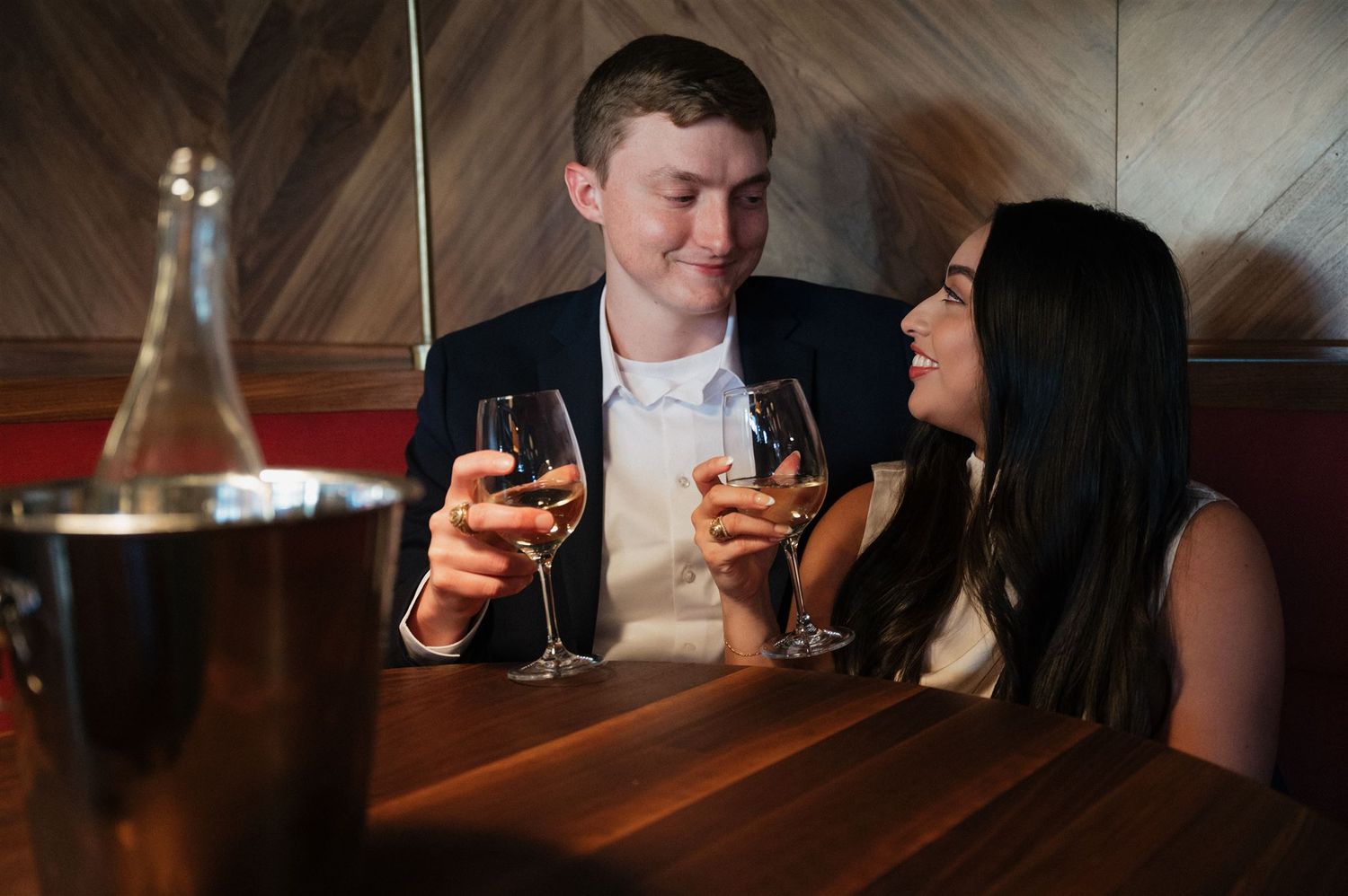 Couple enjoying wine and conversation in an upscale restaurant setting.