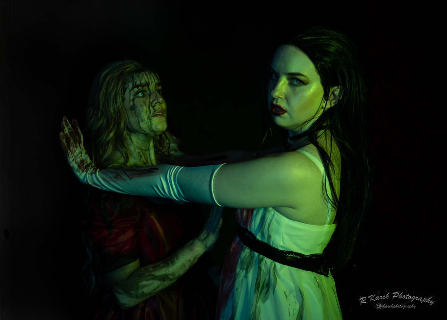 Dramatic scene of two performers in period costumes acting out a confrontation under green lighting.
