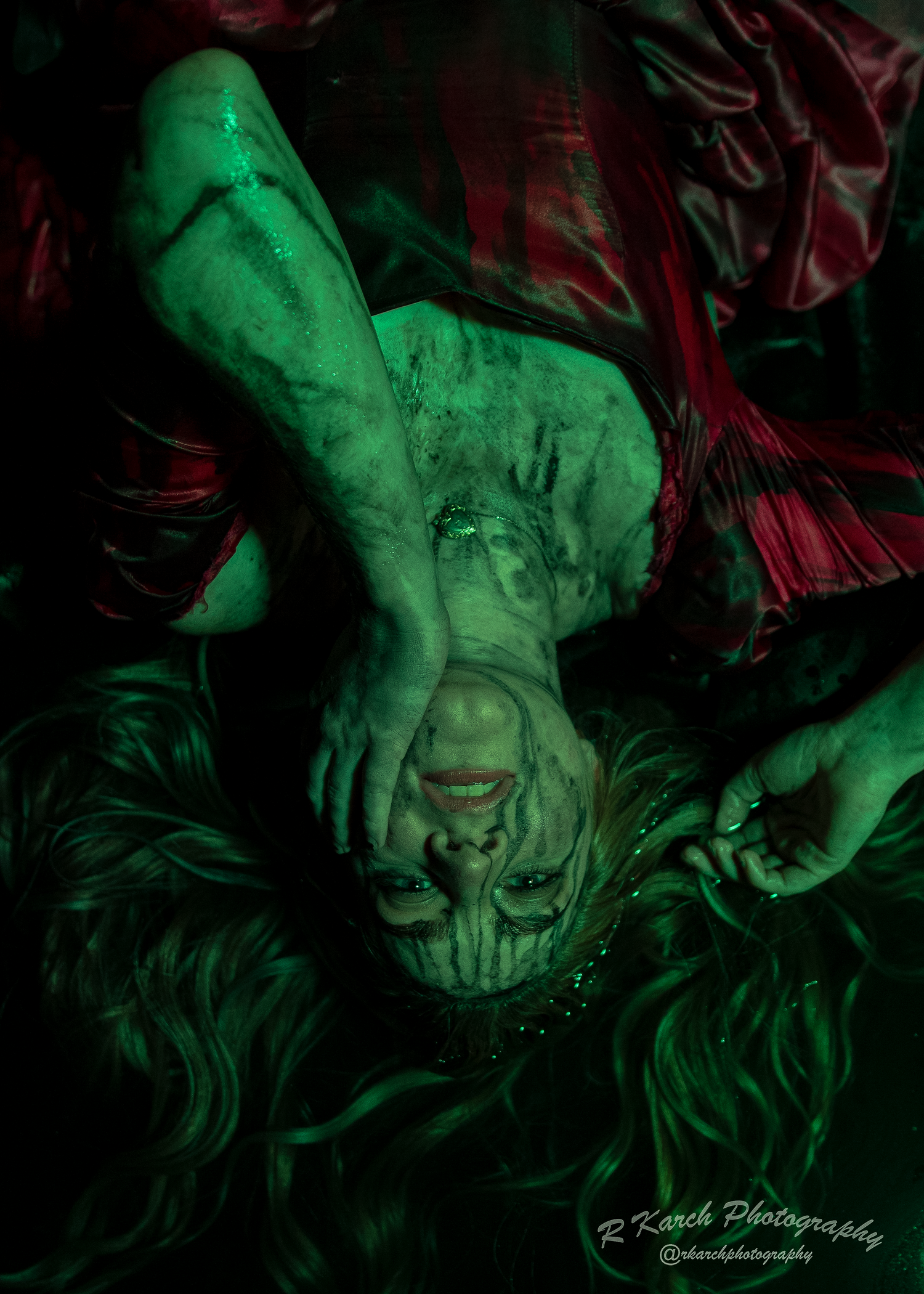 Dramatic upside-down portrait in green lighting creates eerie horror atmosphere.