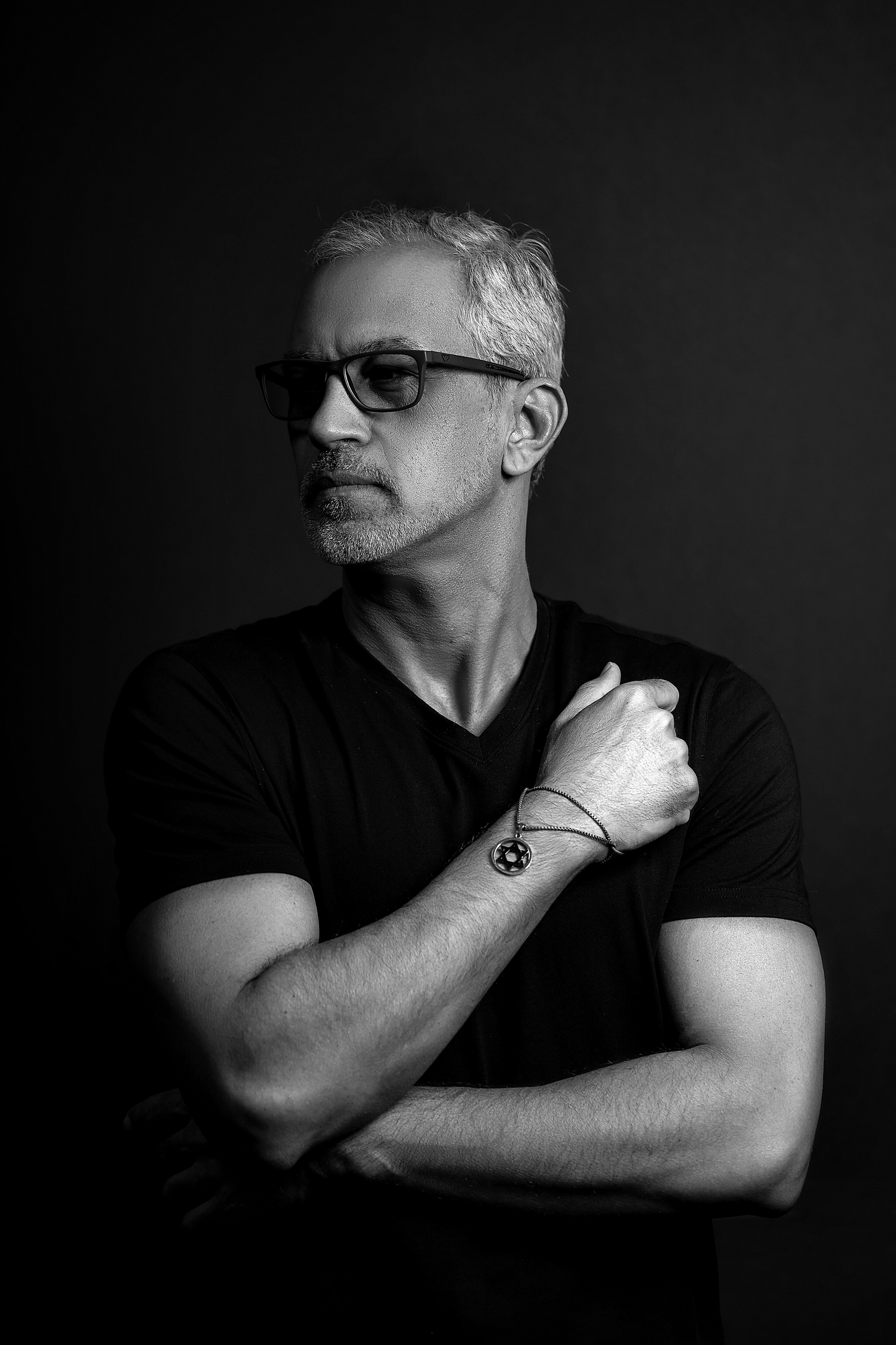 Moody black and white portraits of person in dark t-shirt with dramatic shadows.