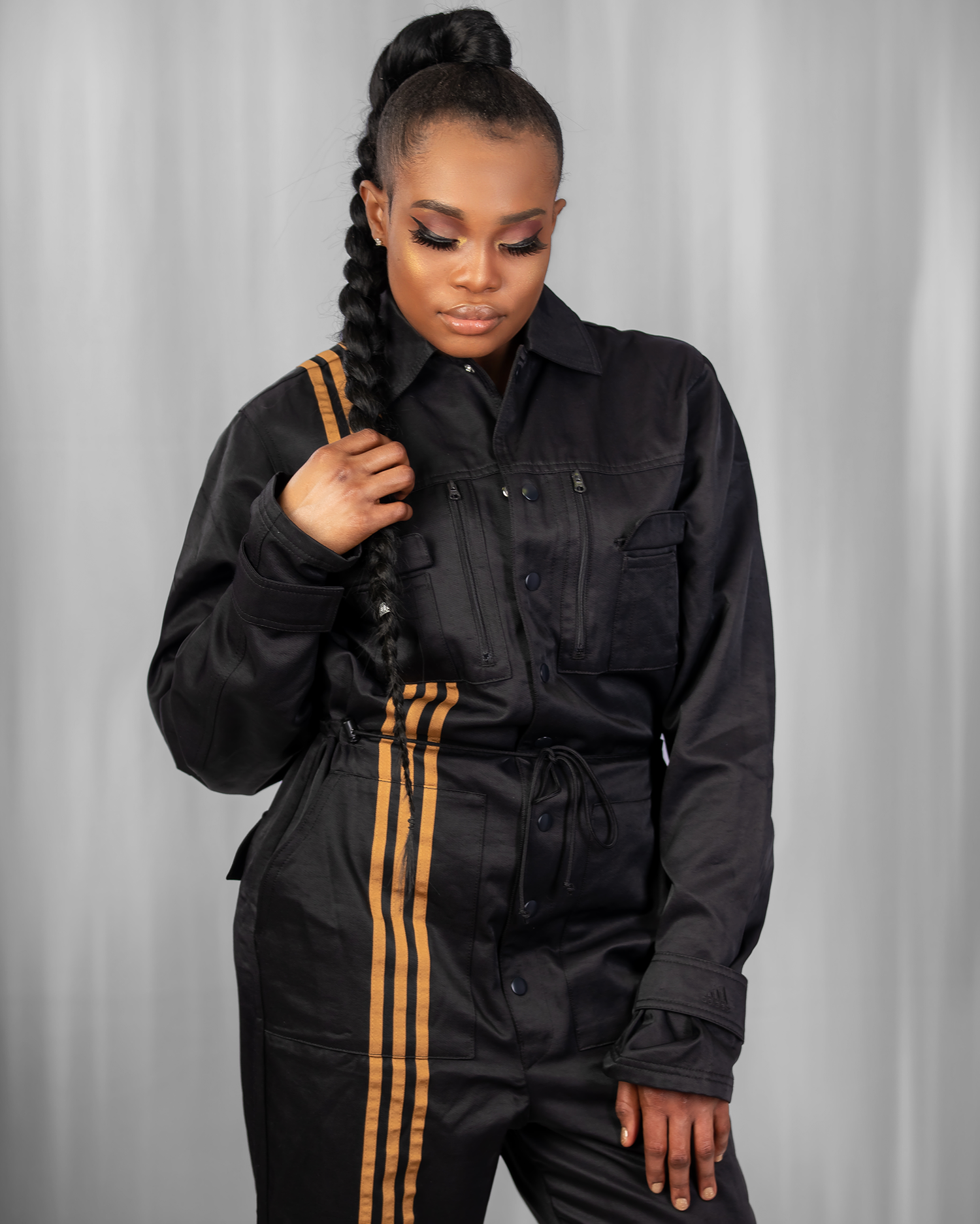 Stylish black jumpsuit with orange stripes features utility pockets and a drawstring waist for an urban streetwear look.