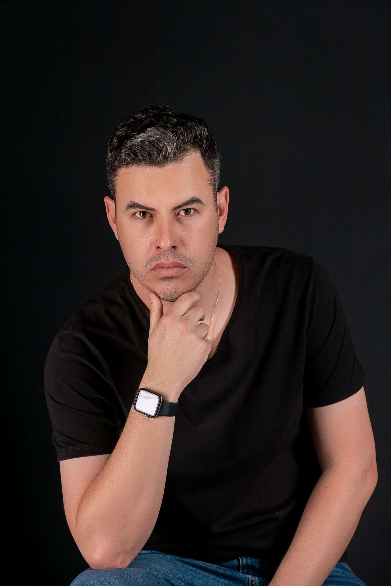 Artistic portrait series showing thoughtful expressions in black shirt against dark backdrop.