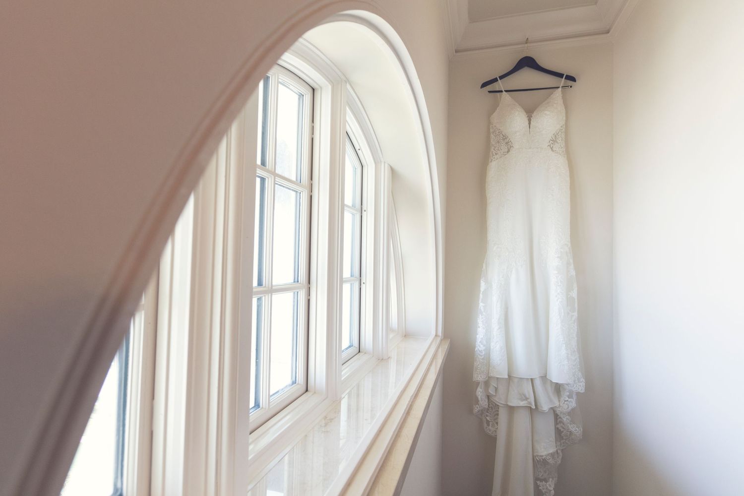 Arched windows with white curtains create a bright, airy dressing room space.
