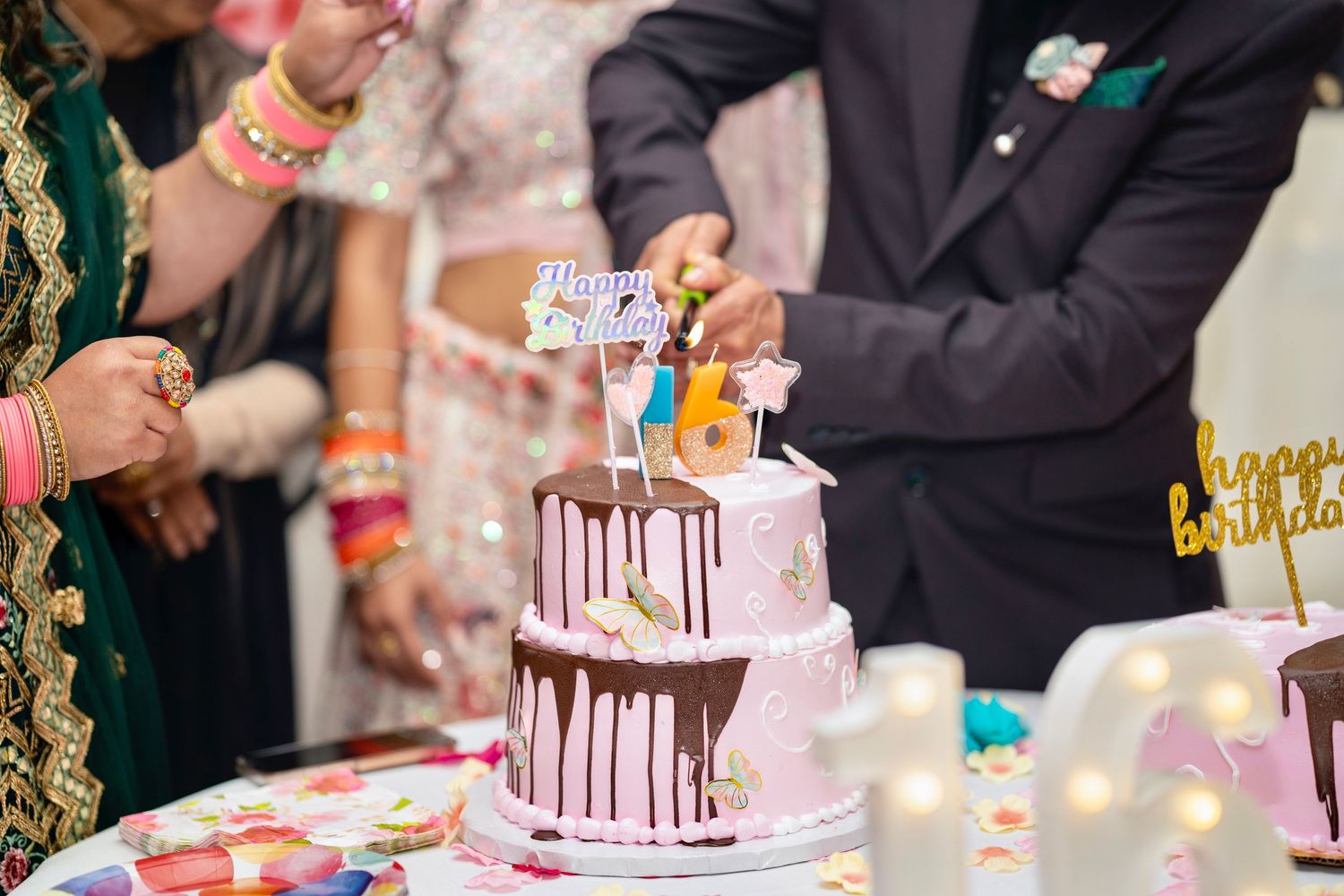 Wedding cake cutting ceremony with drip-style decorated white and pink tiered cake.