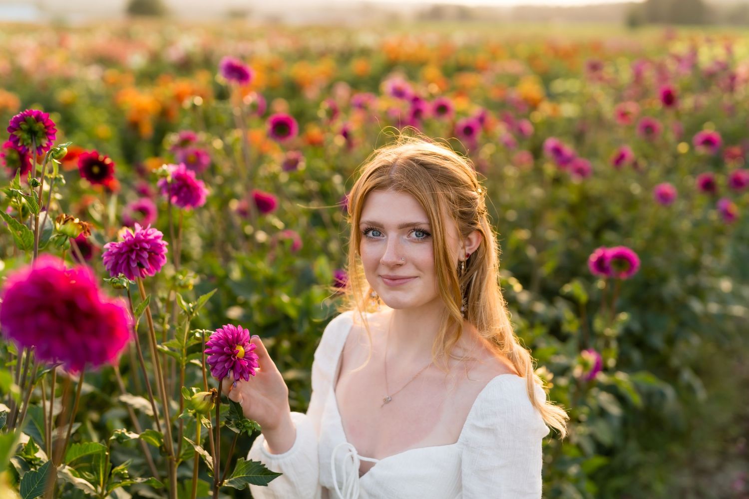 Portrait in a vibrant dahlia flower field at golden hour with warm sunlight.