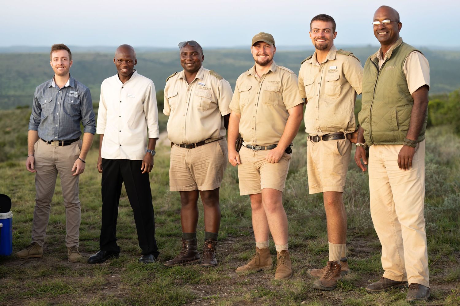 Safari guides and staff lined up outdoors in khaki uniforms.