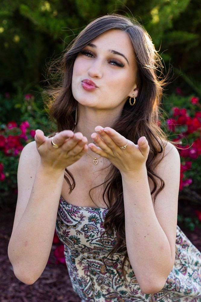 senior from fhs blowing a kiss to the camera with roses behind her
