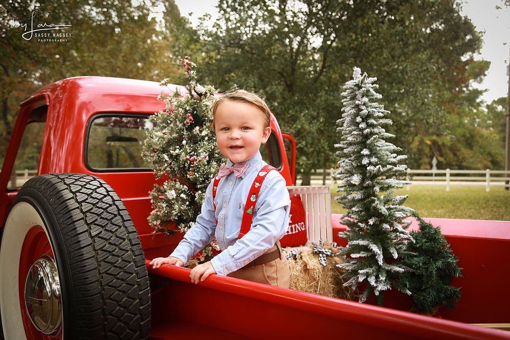 A happy Toddler in the back of a Christmas Decorated 1954 Red Ford during Christmas in the Country Photos in Waller, TX.