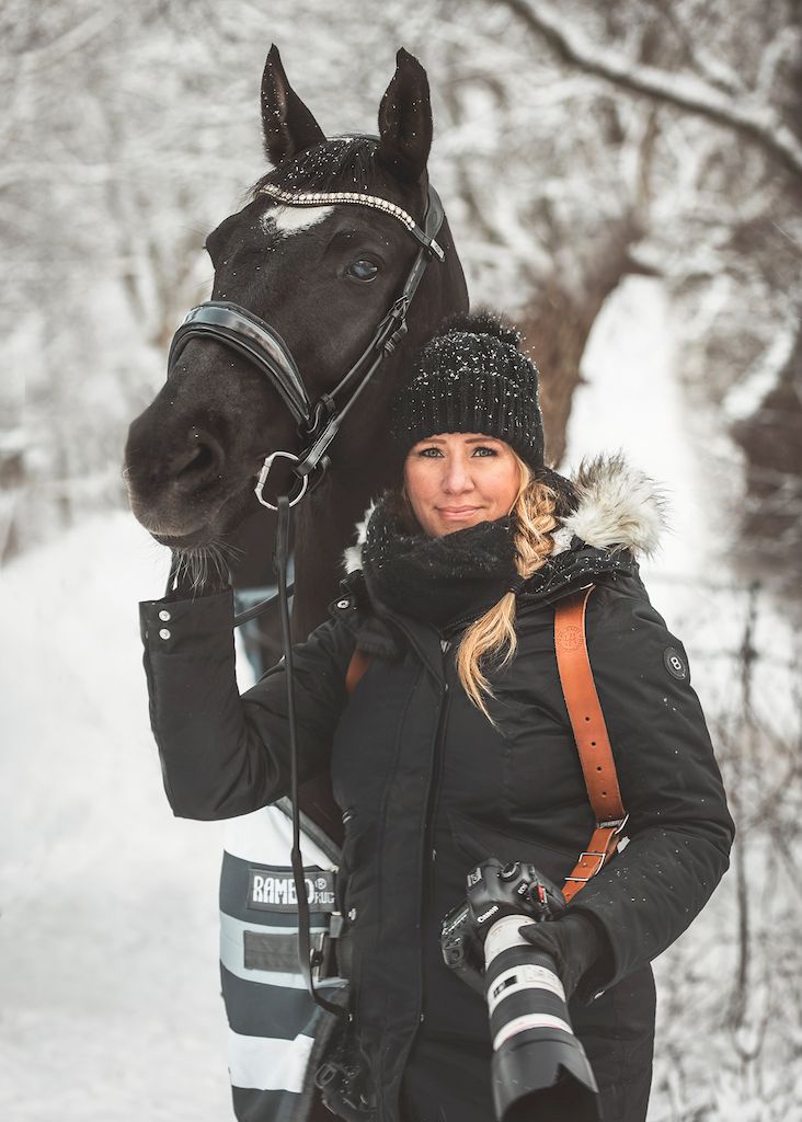Porträtt på hästfotograf Anna Jarlhäll med en svart häst och det är vinter.