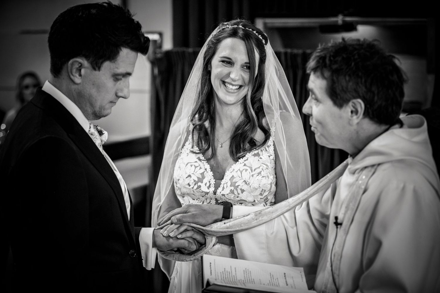 Black and white photo captures candid reactions during wedding ceremony.