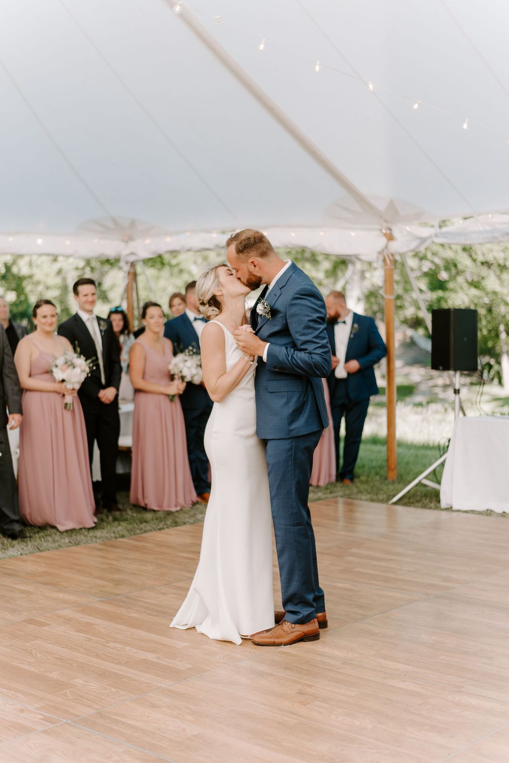 Romantic first dance moment under string lights at an outdoor tented wedding reception.