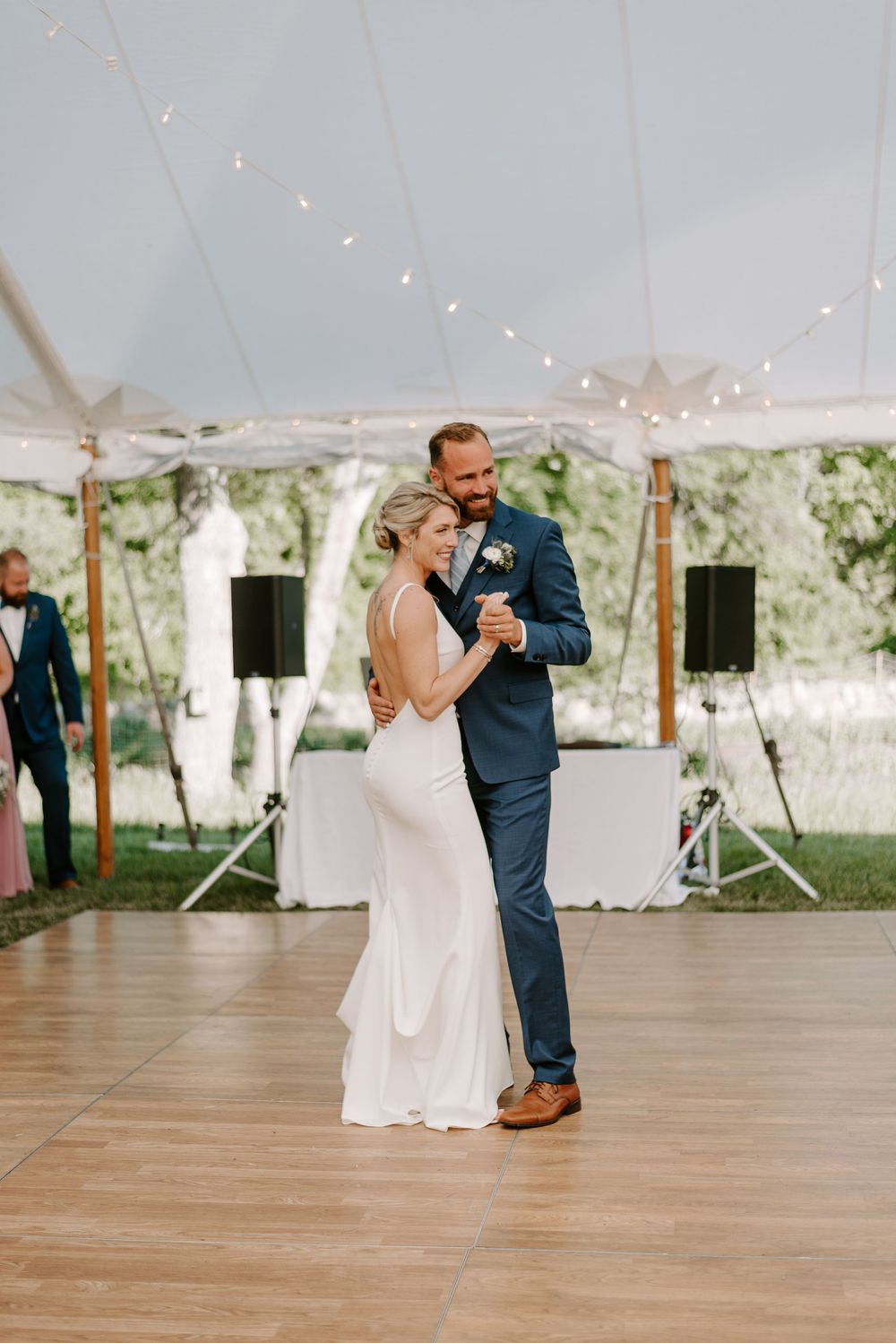Intimate dance moment under string lights at an outdoor tented wedding reception.