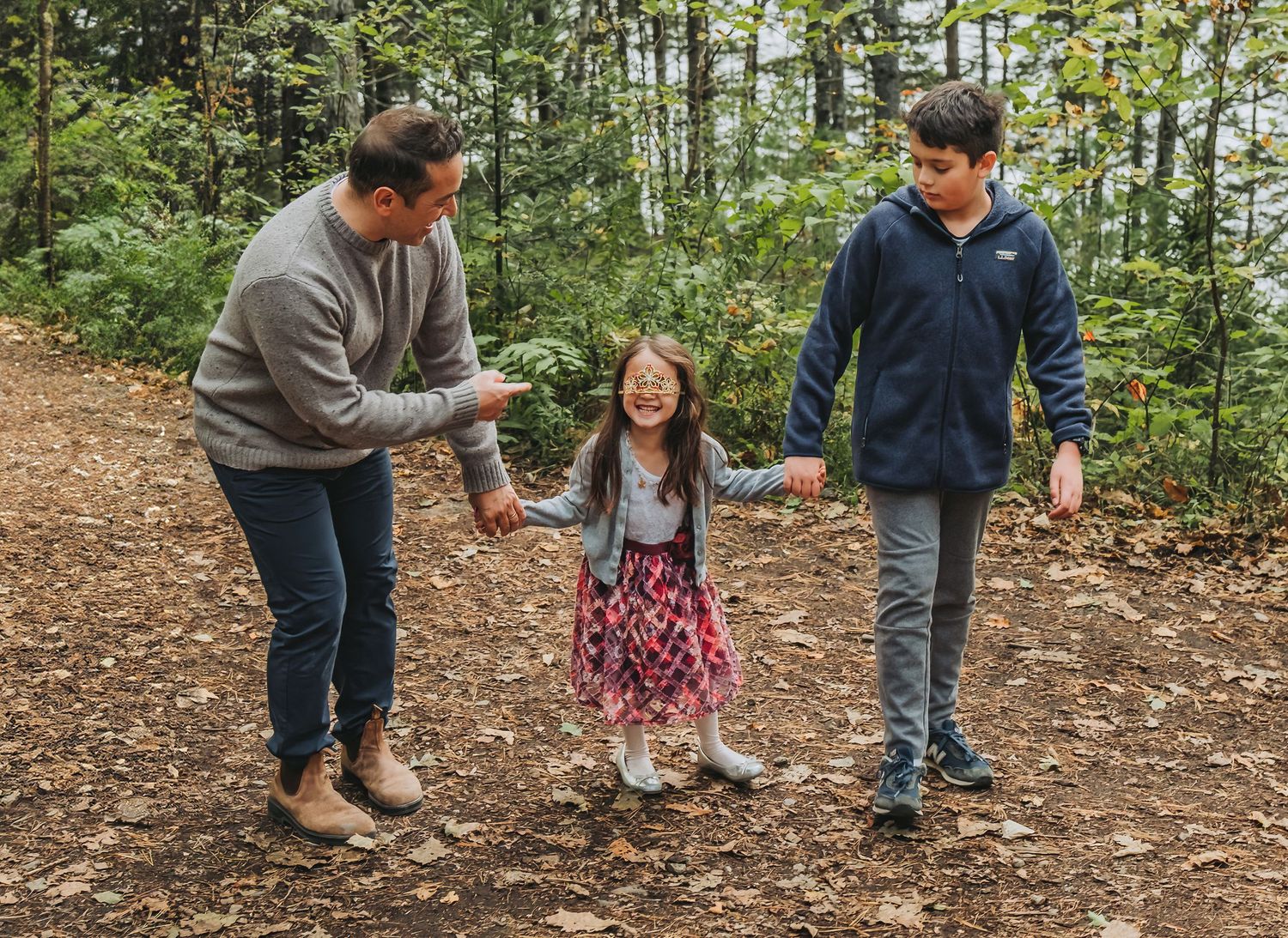 A dad laughs with his daughter and son after his daughter's crown accidentally falls on her face.