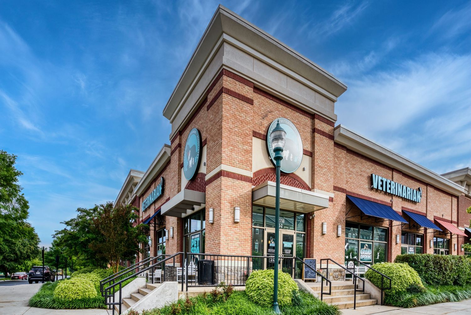 Modern brick retail building with large windows and ornate exterior features against a bright blue sky.