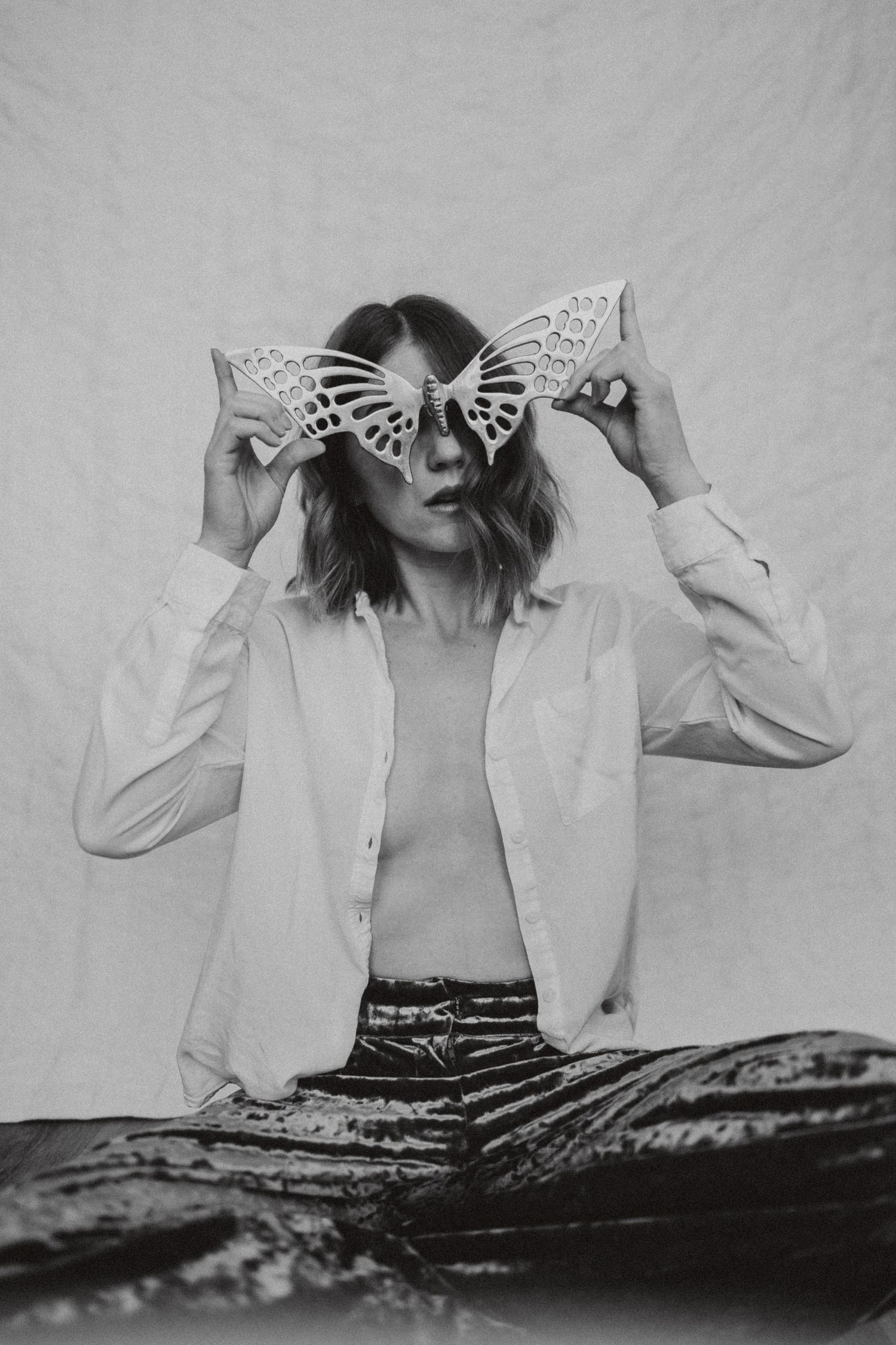 Artistic black and white portrait featuring decorative butterfly-shaped eyewear and a light blazer.
