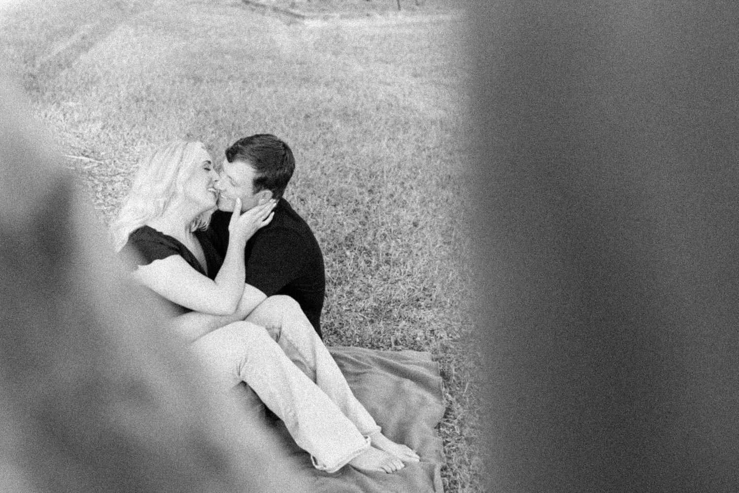 man and woman kiss sitting on a blanket