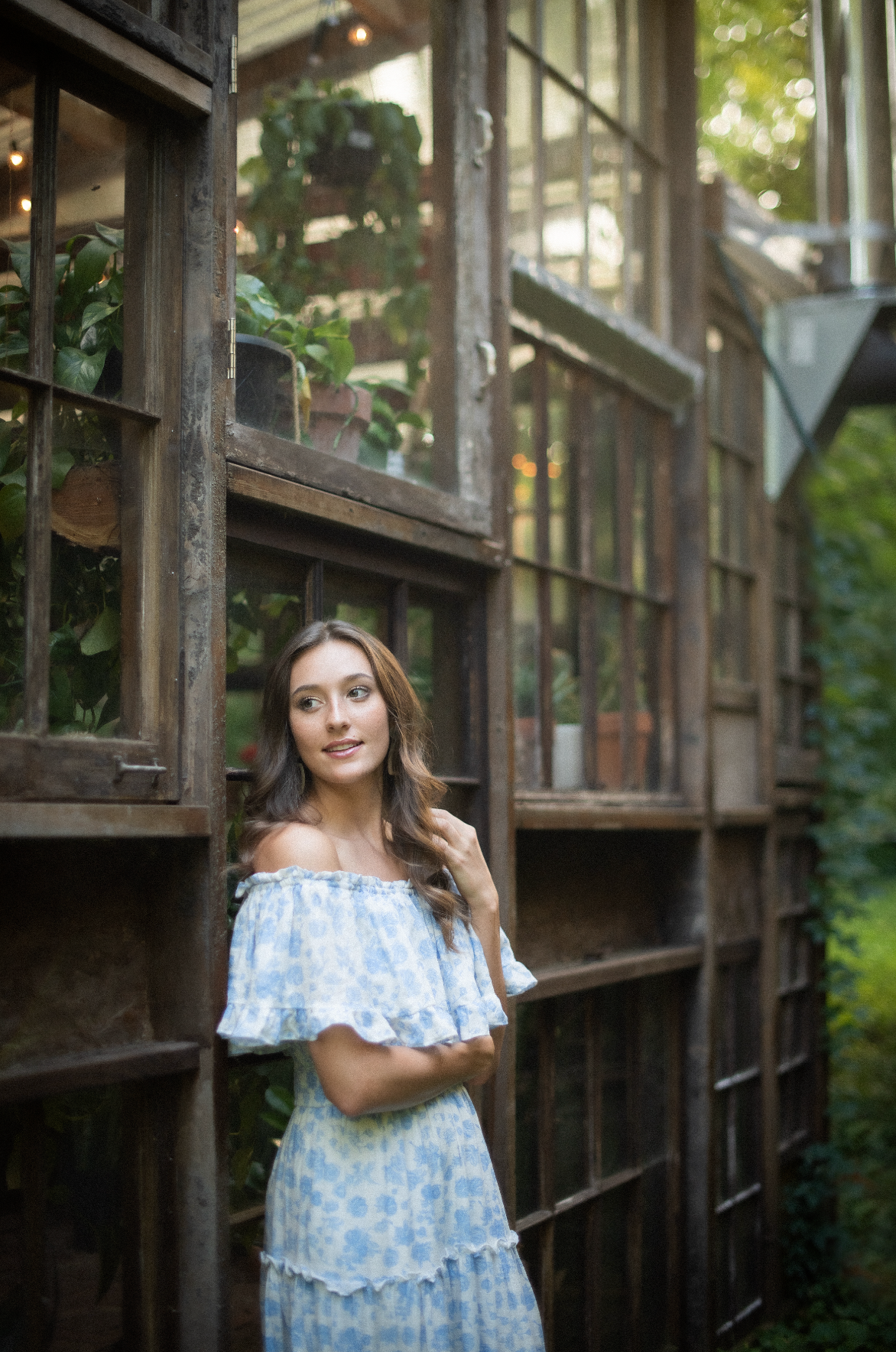 Portrait session at a rustic greenhouse featuring a light blue off-shoulder dress.