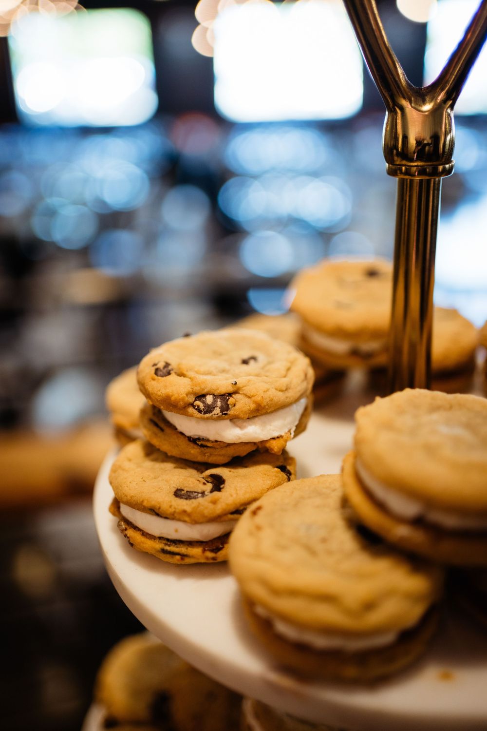 Chocolate chip cookie ice cream sandwiches displayed on tiered serving stand.