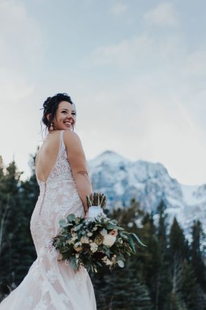 Bride stands with back towards camera in front of mountains