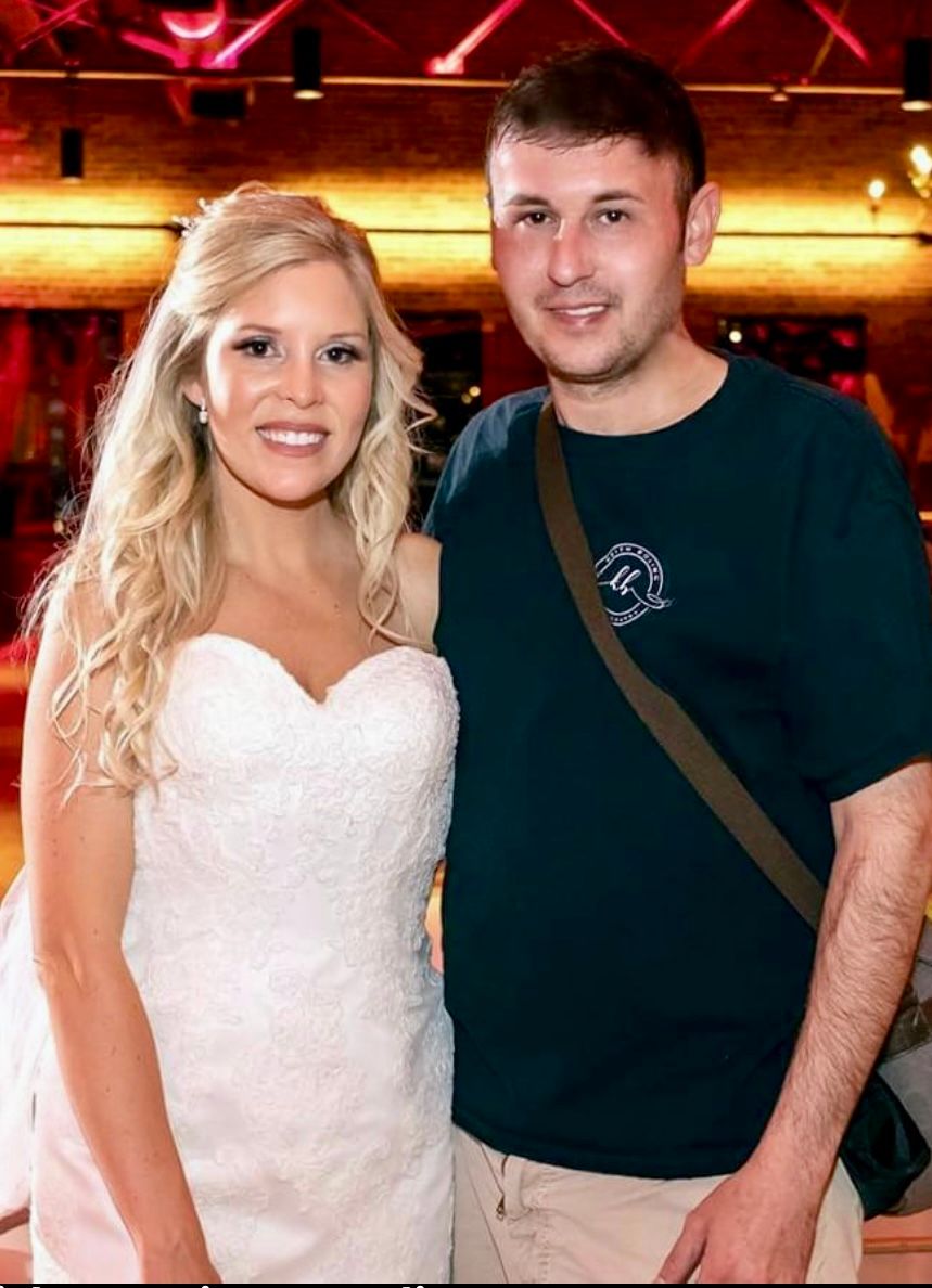Wedding reception photo of couple under warm lighting with camera strap visible.