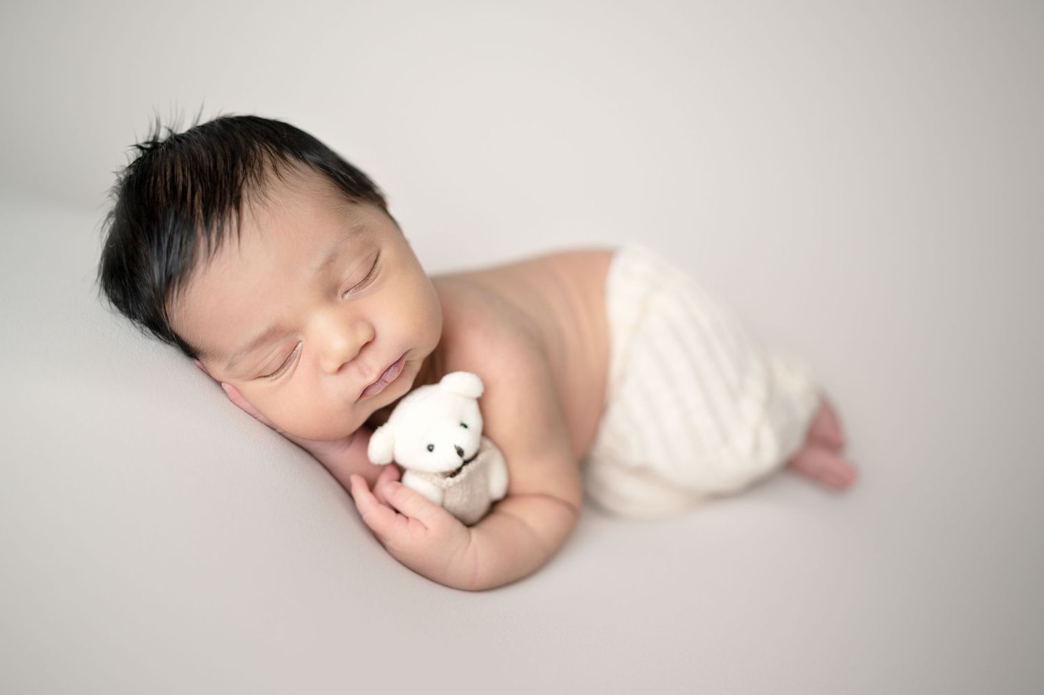 A peaceful newborn portrait with soft lighting and delicate details against a light background.
