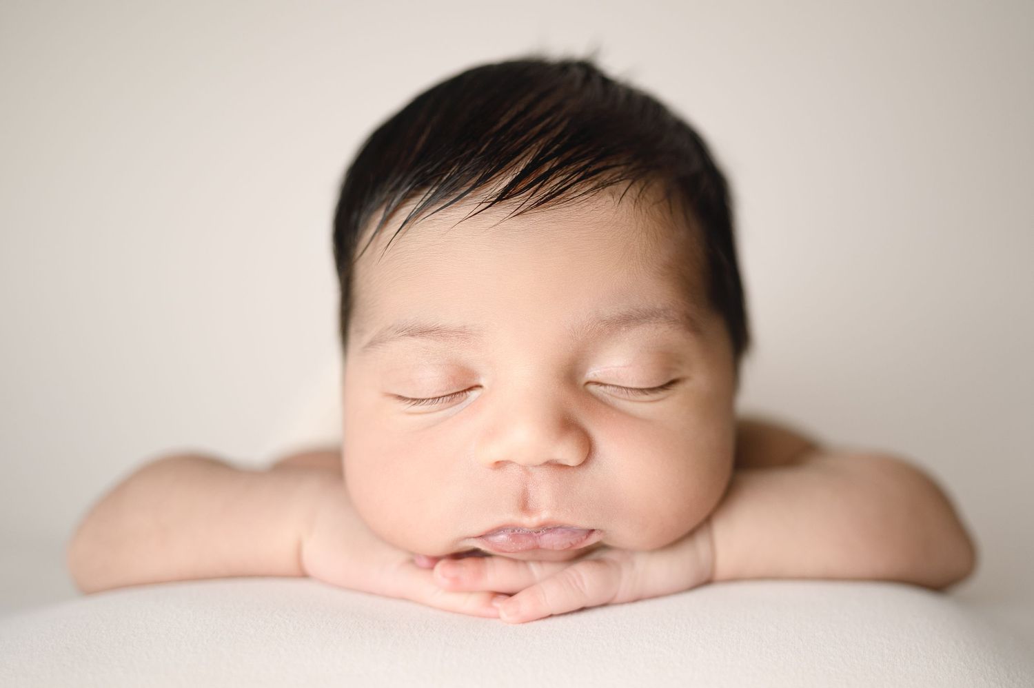 Minimalist newborn photography featuring gentle overhead lighting and peaceful expression.