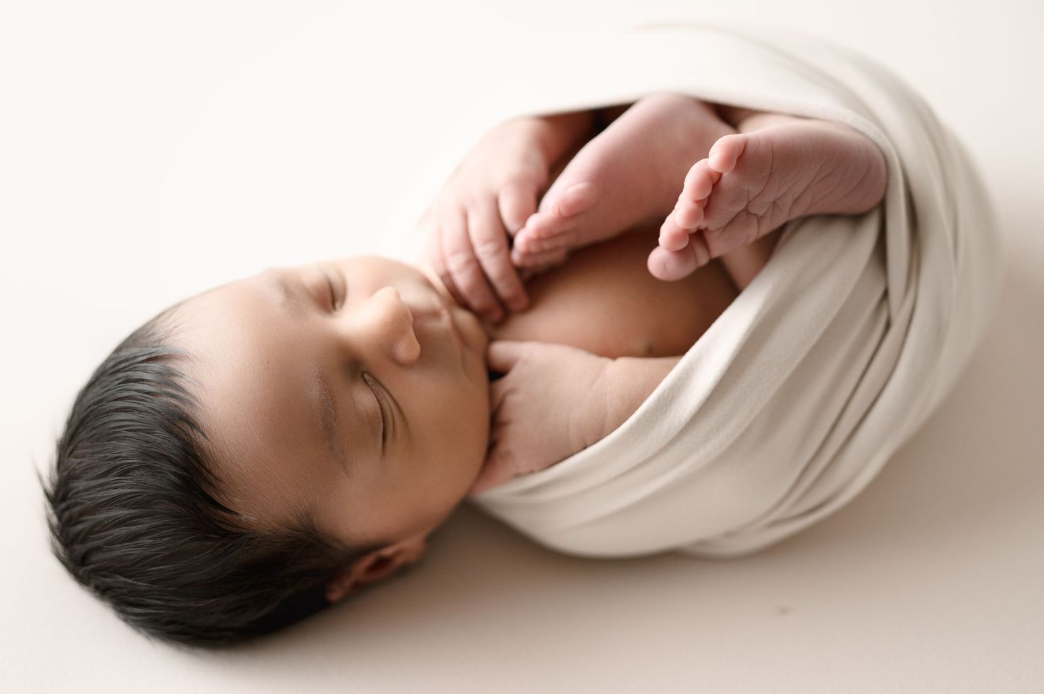 Artistic newborn portrait showing gentle curves and soft wrapping in natural light.
