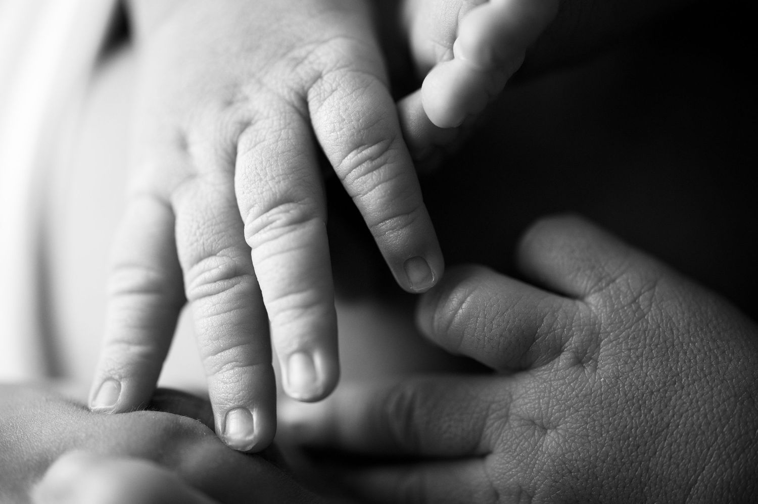 Black and white macro photograph of tiny newborn fingers and details.