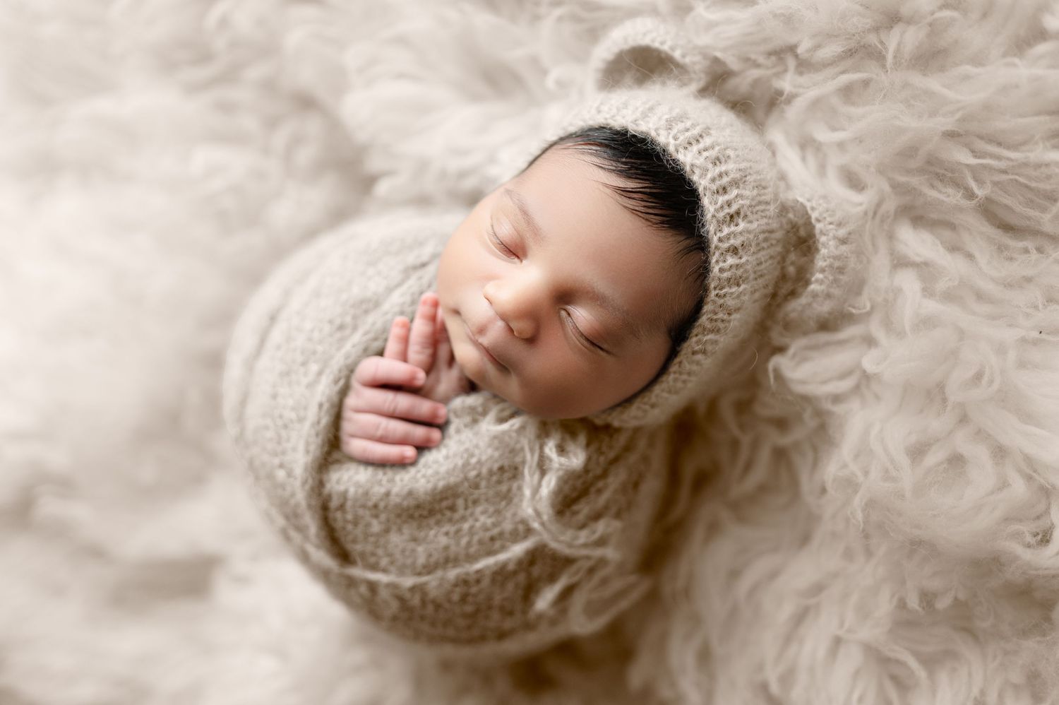 Series of artistic newborn portraits with baby swaddled in cream colored wrap on white backdrop.